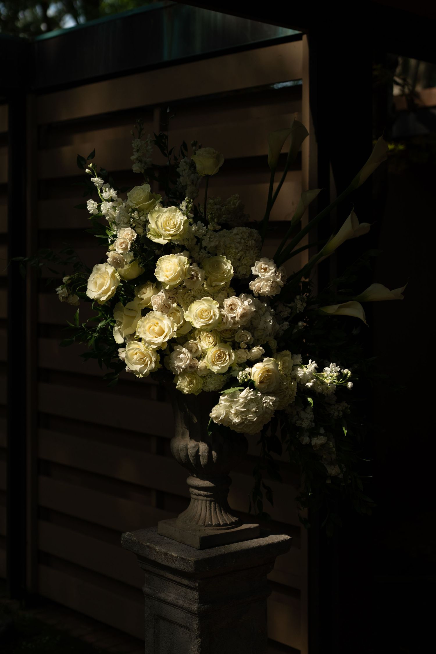 Elegant white roses and floral arrangements illuminated in a dark setting.
