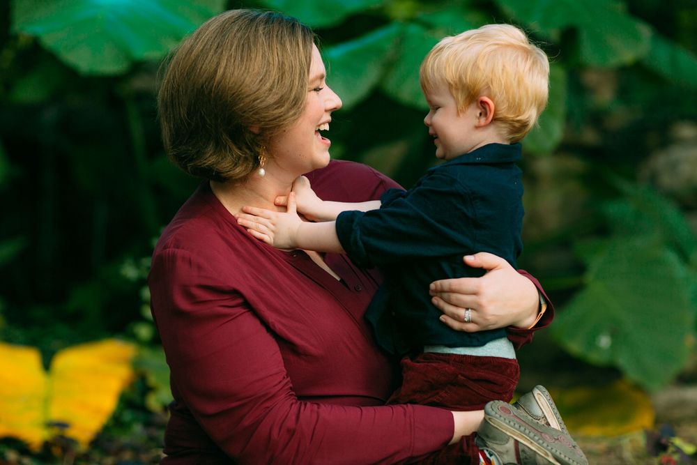 Delightful family photoshoot in a lush green garden setting with bokeh lights creating a magical atmosphere.