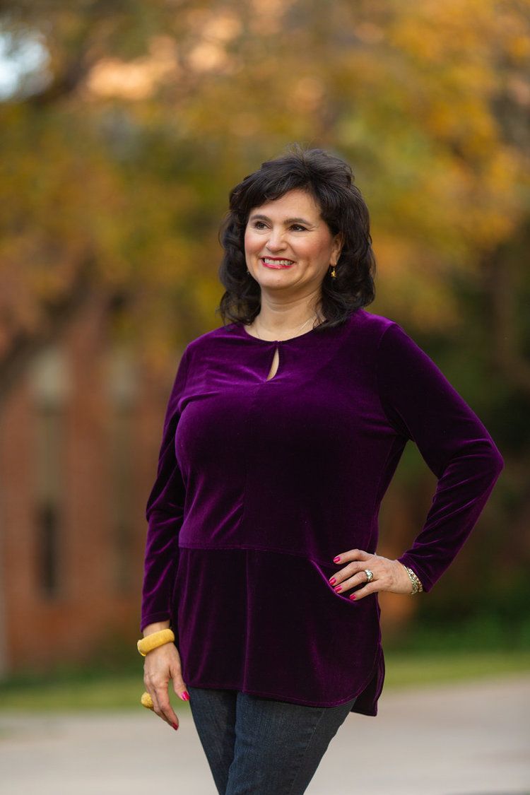 Someone wearing a purple velvet top poses confidently outdoors during autumn.