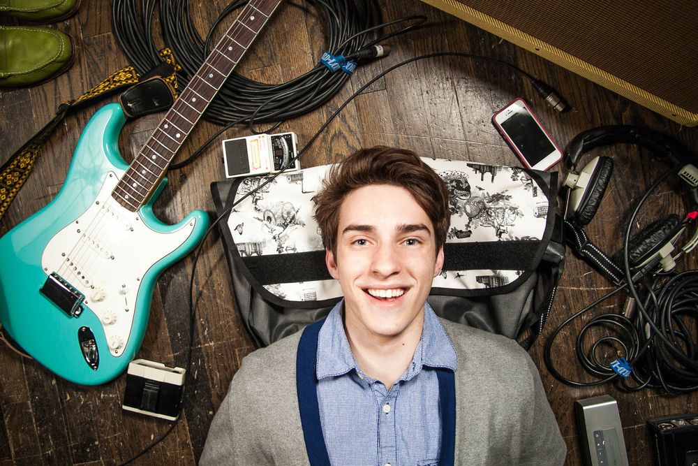 Musicians poses with electric guitar and equipment in creative studio setting.