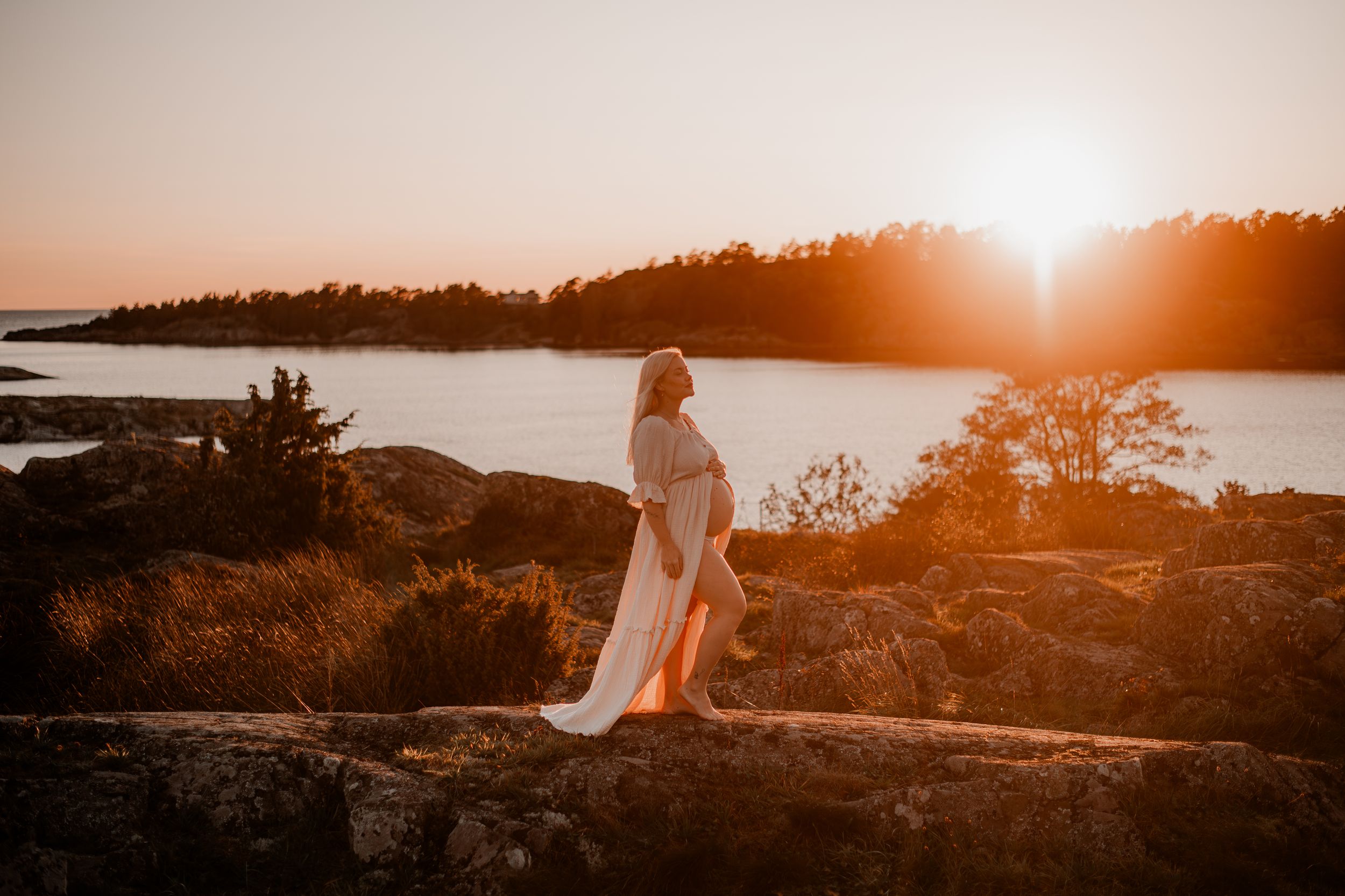 Gravid kvinna på klippa i solnedgången på Torö