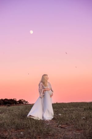 Gravid kvinna under rosa himmel och måne