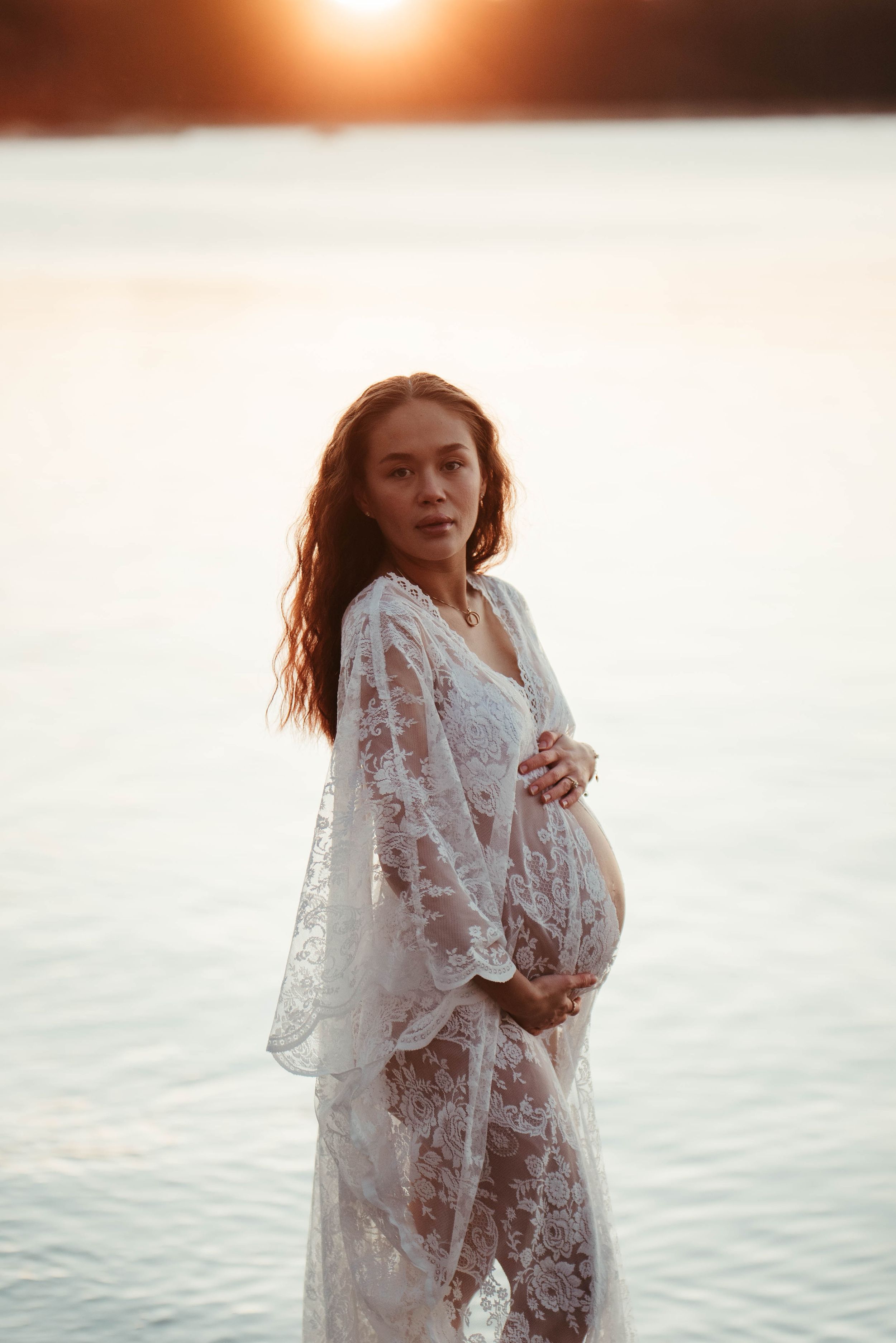 Gravid tjej i spetsklänning i soluppgången en frostig morgon