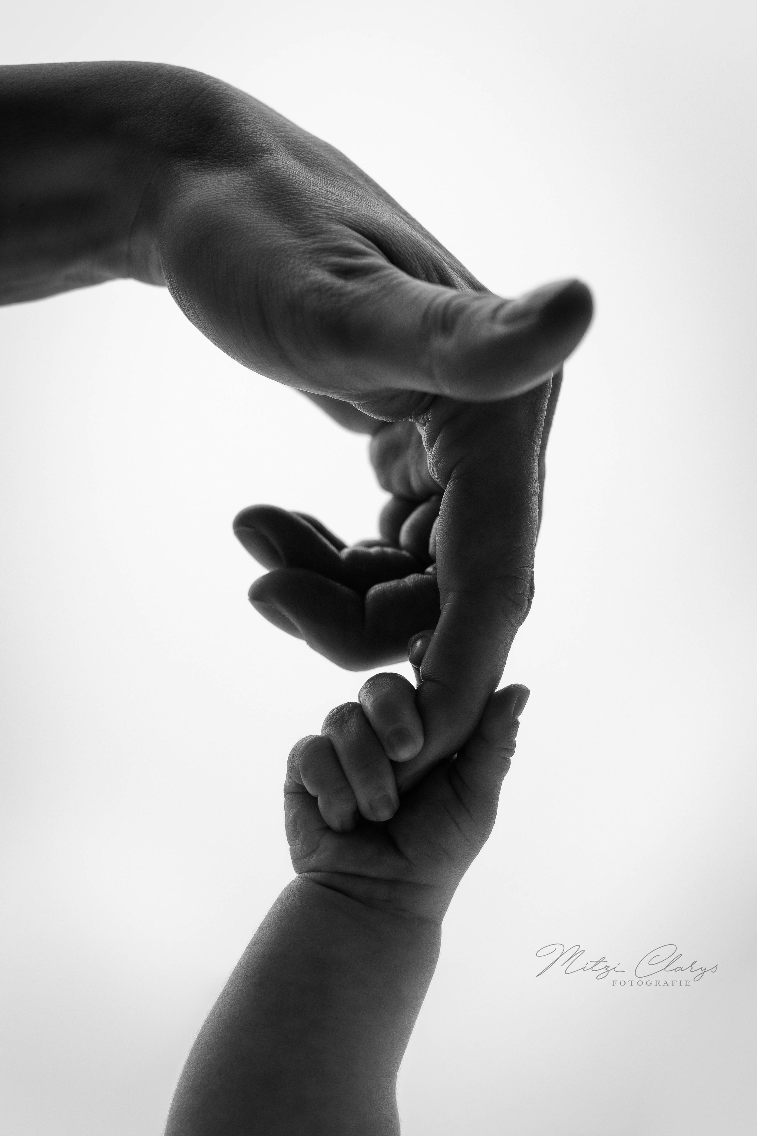 Zwart wit foto van een close up van handje baby en hand moeder tijdens newbornshoot in studio Goes