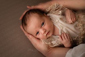 Pasgeboren meisje in handen van mama tijdens newbornshoot