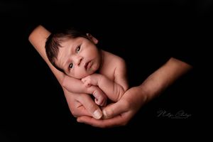 pasgeboren baby in handen van papa met zwarte achtergrond tijdens newbornshoot, Zeeland