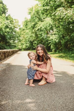 A sweet moment captured on a tree-lined path with stone walls.