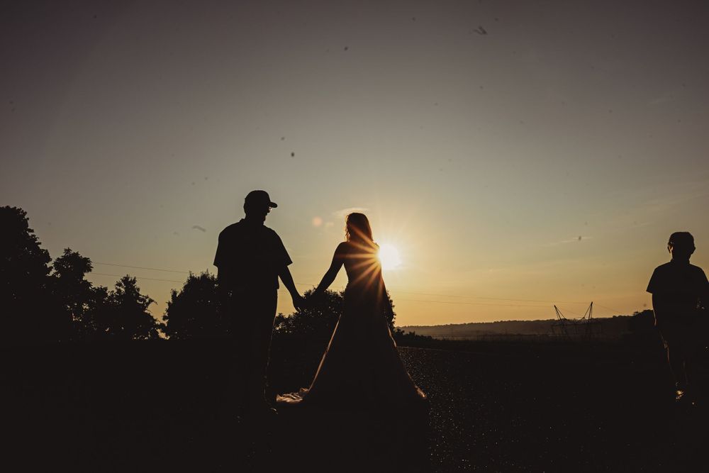Silhouettes of a couple against a dramatic sunset sky creating a romantic atmosphere.
