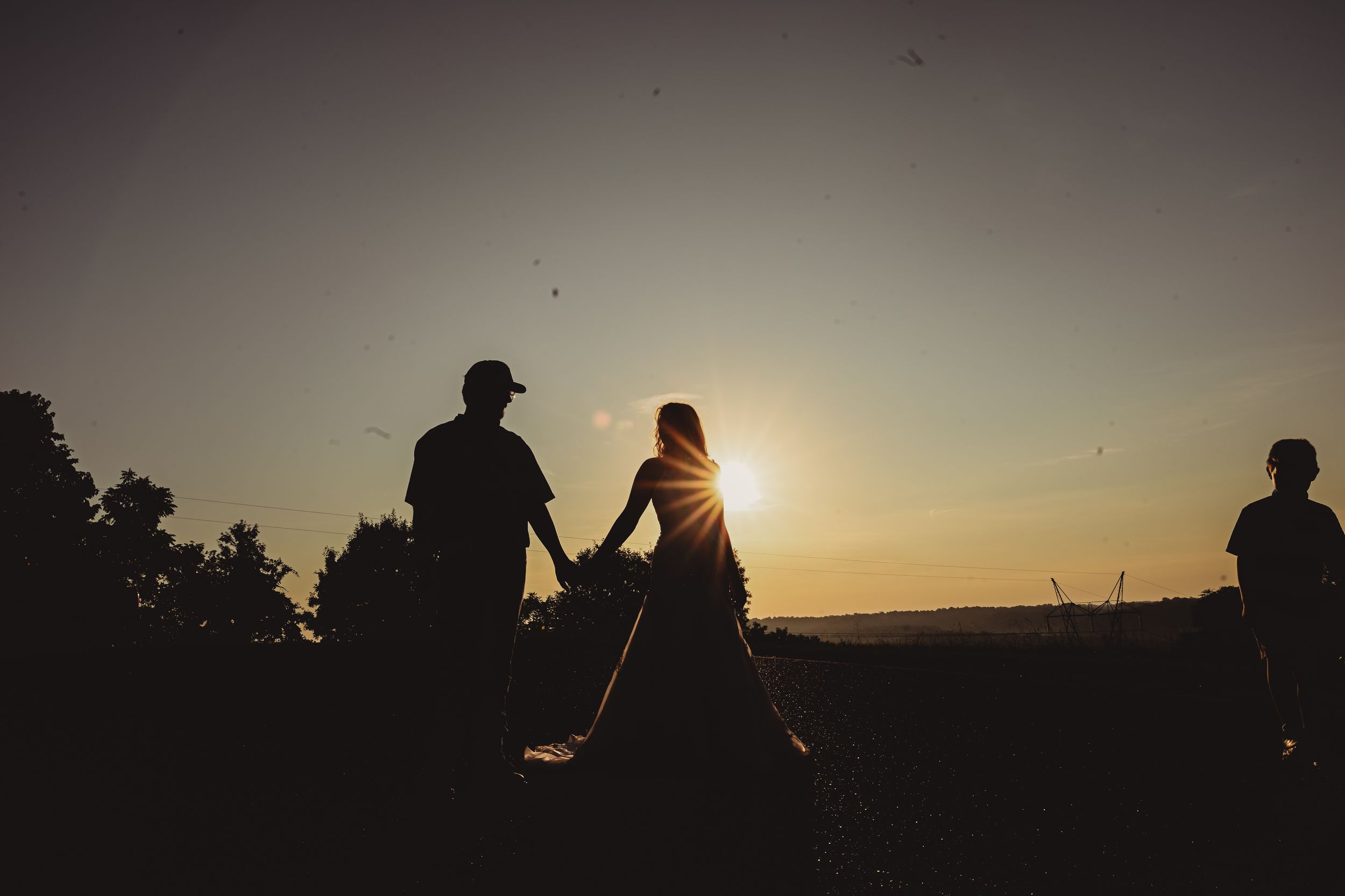 Silhouettes of a couple against a dramatic sunset sky creating a romantic atmosphere.