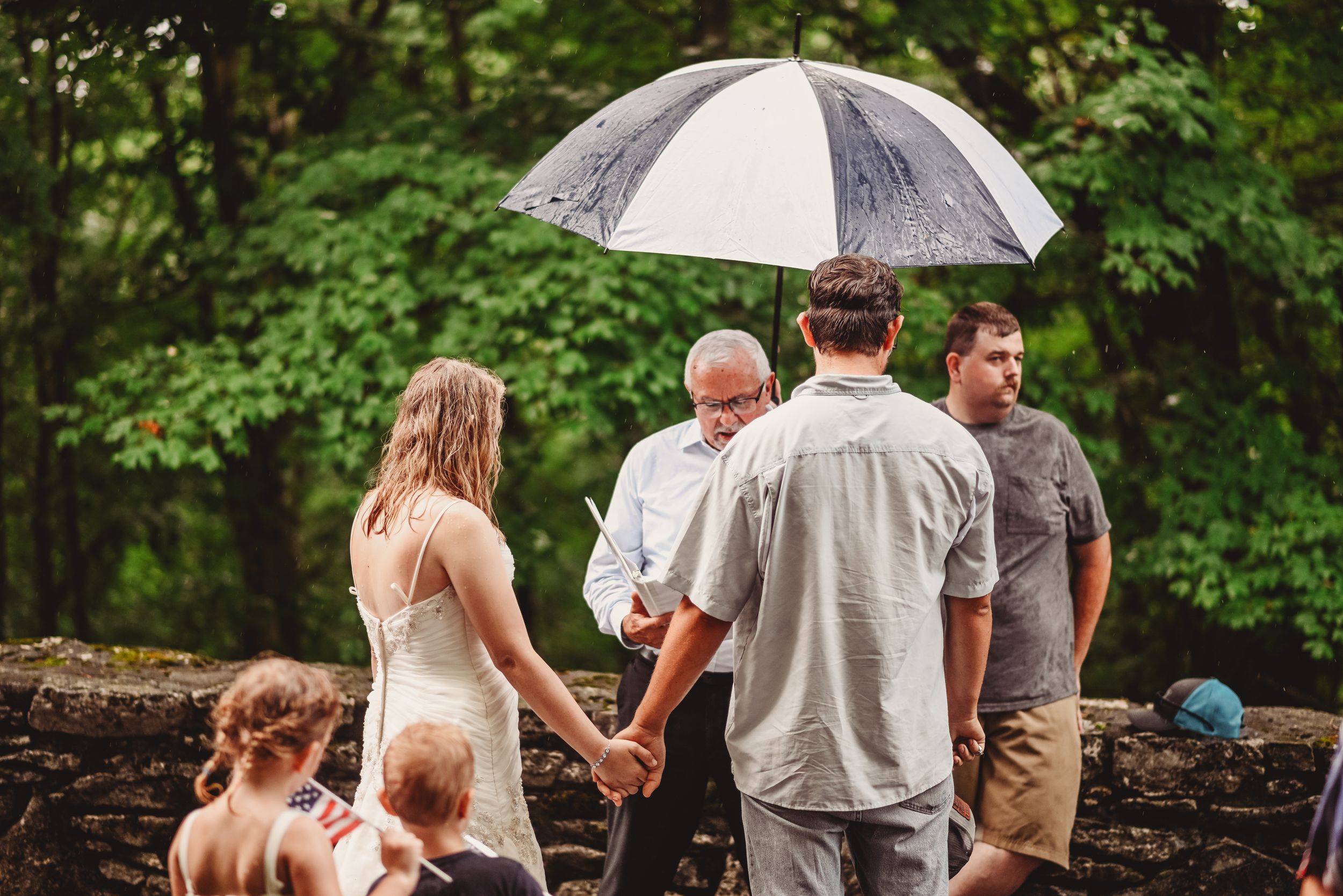 Group walking together under a white umbrella on a sunny day in a park setting.