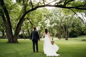 A wedding couple walking together through a scenic grove of trees in Tulsa oklahoma.