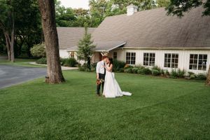 A romantic wedding photo on a manicured lawn in front of an elegant house in Tulsa Oklahoma