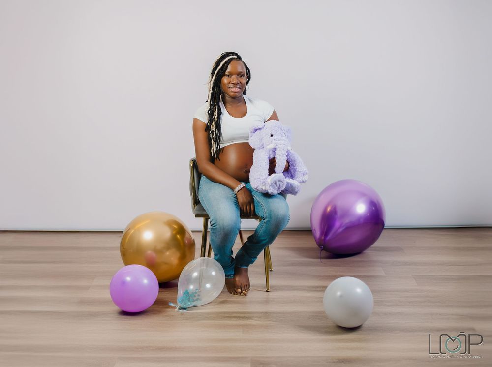 Athletic woman in workout attire sits on floor with colorful exercise balls in bright studio setting.