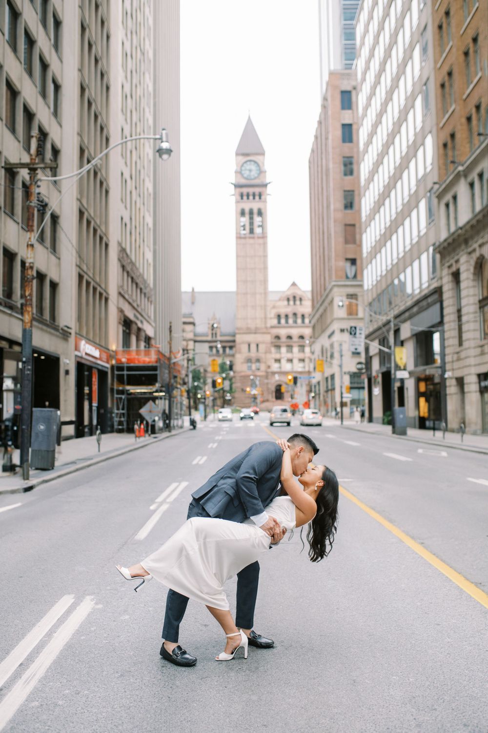 A couple shares a romantic moment in front of Toronto's Old City Hall clock tower.