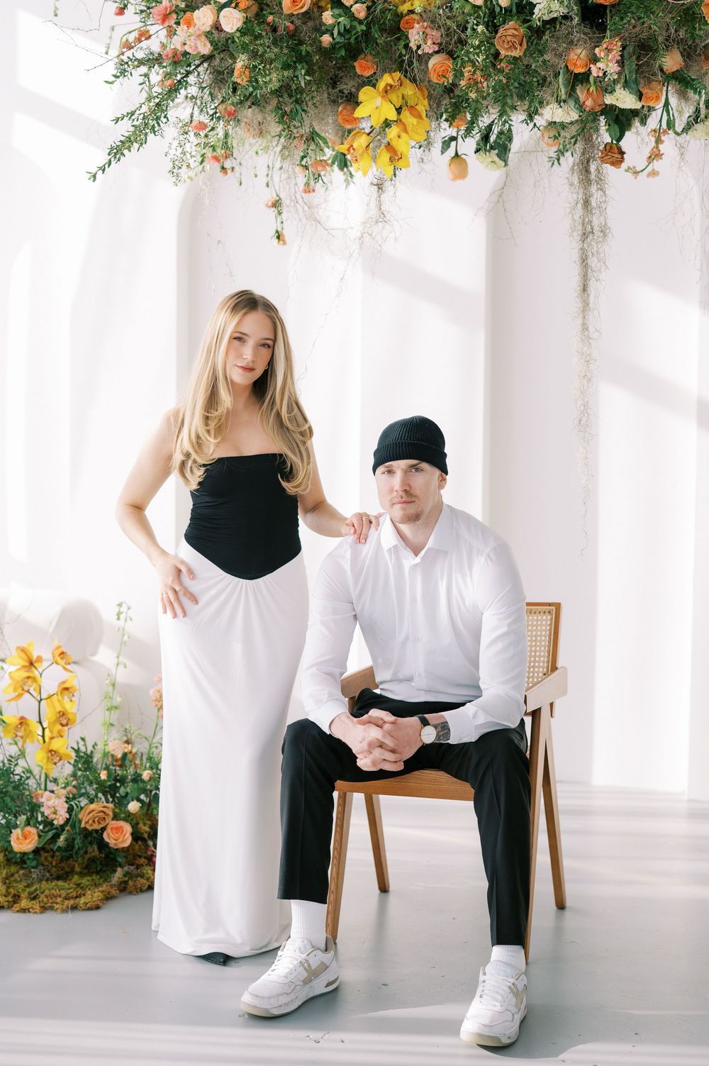 Modern minimalist photoshoot featuring people in black and white outfits with floral ceiling decorations.