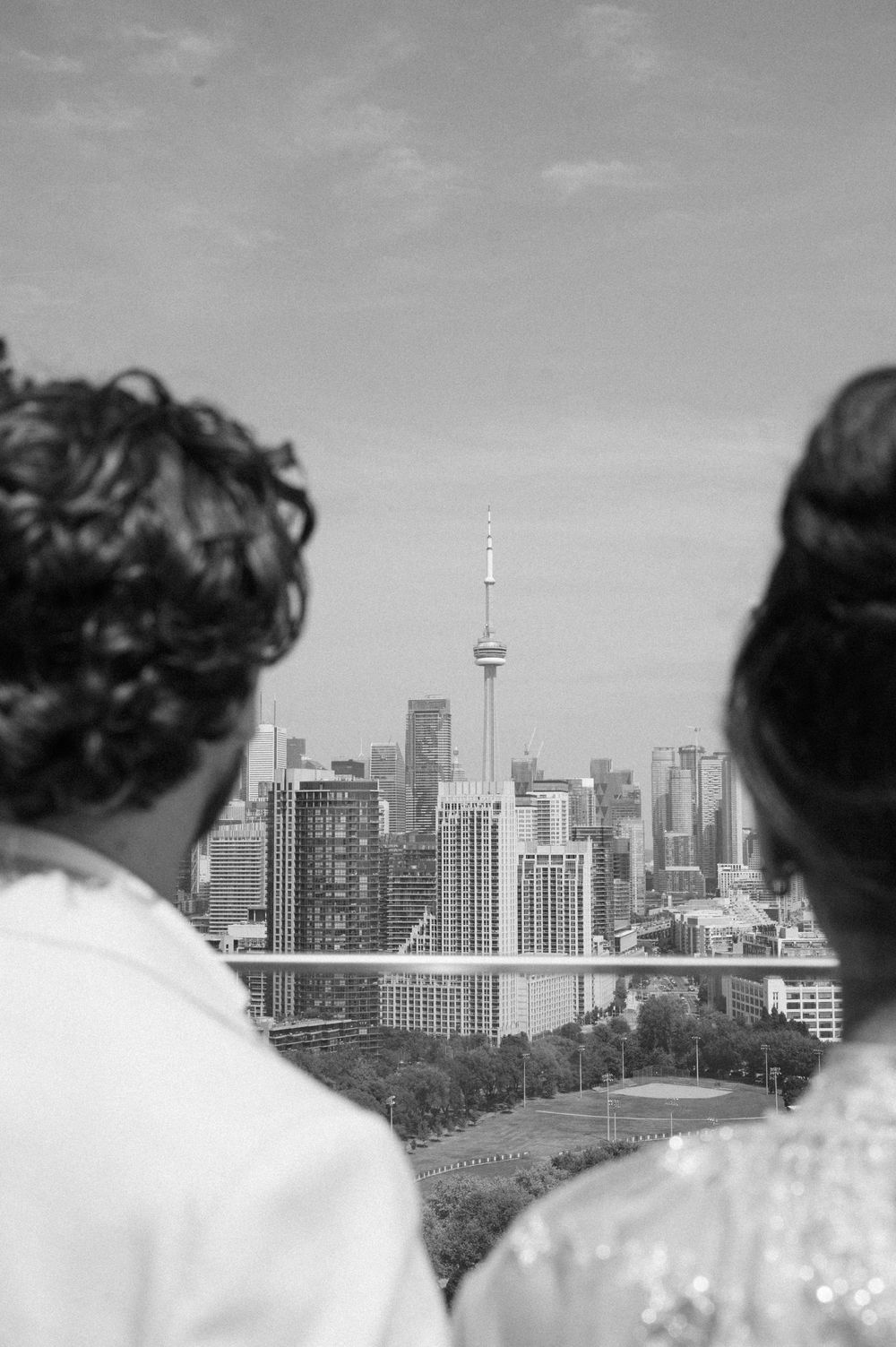 Black and white wedding photo of couple overlooking Toronto skyline with CN Tower in background.