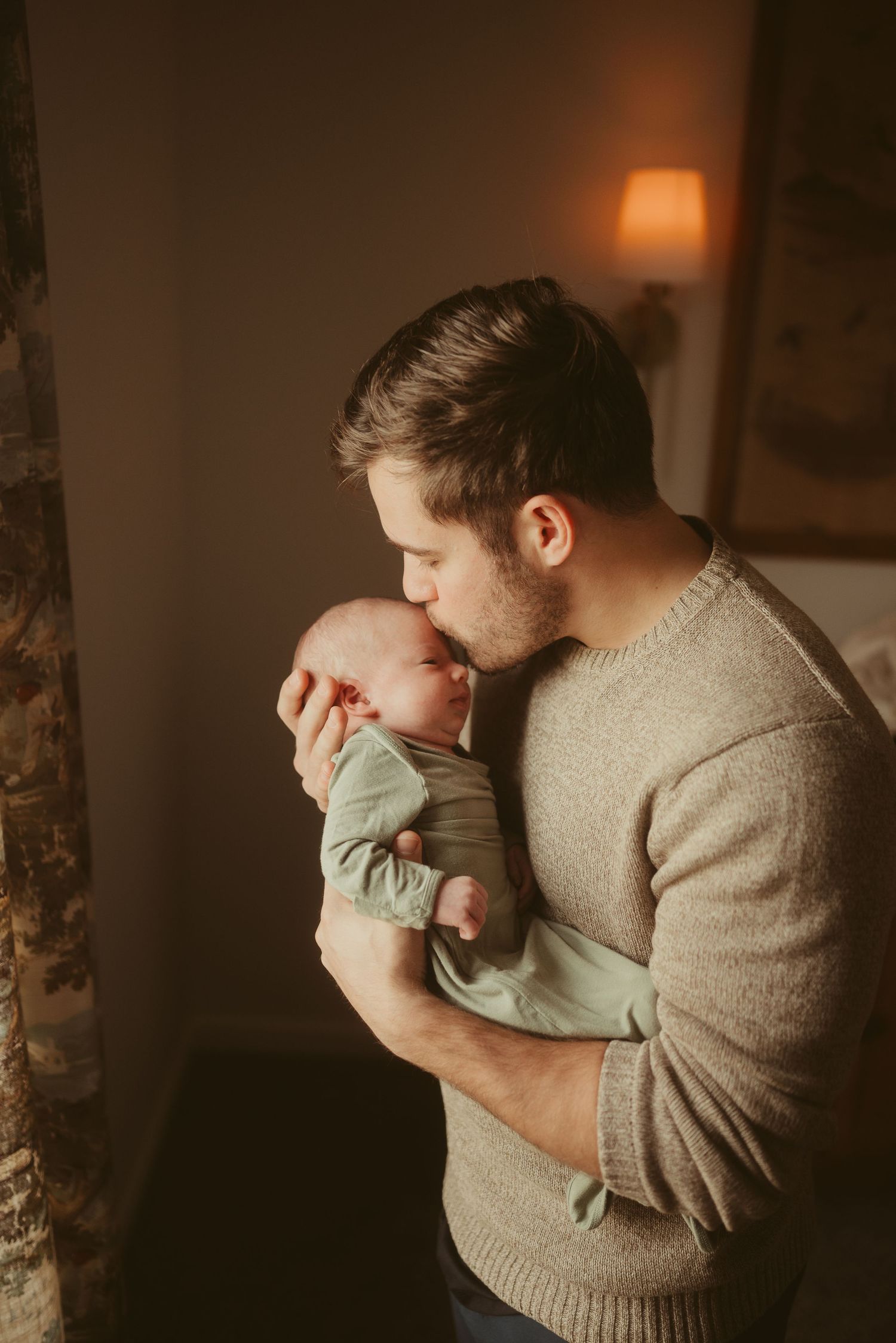 New dad gives firstborn son a kiss in nursery during lifestyle newborn session in Clarksville, Tennessee by Disney Magic Photography