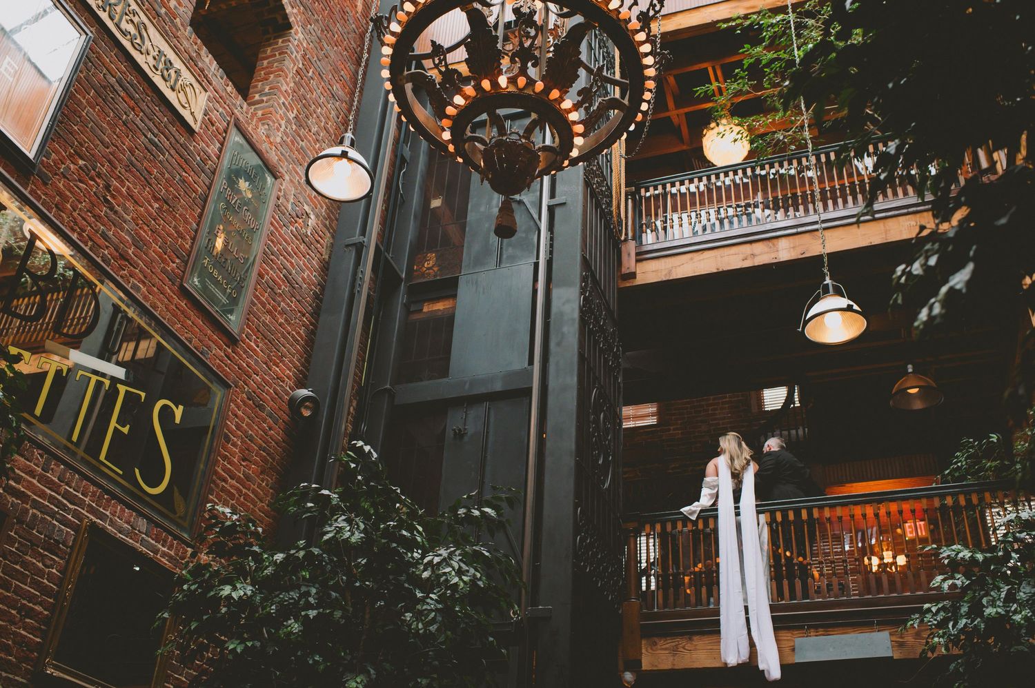 Historic brick building exterior with wrought iron details and hanging lights.