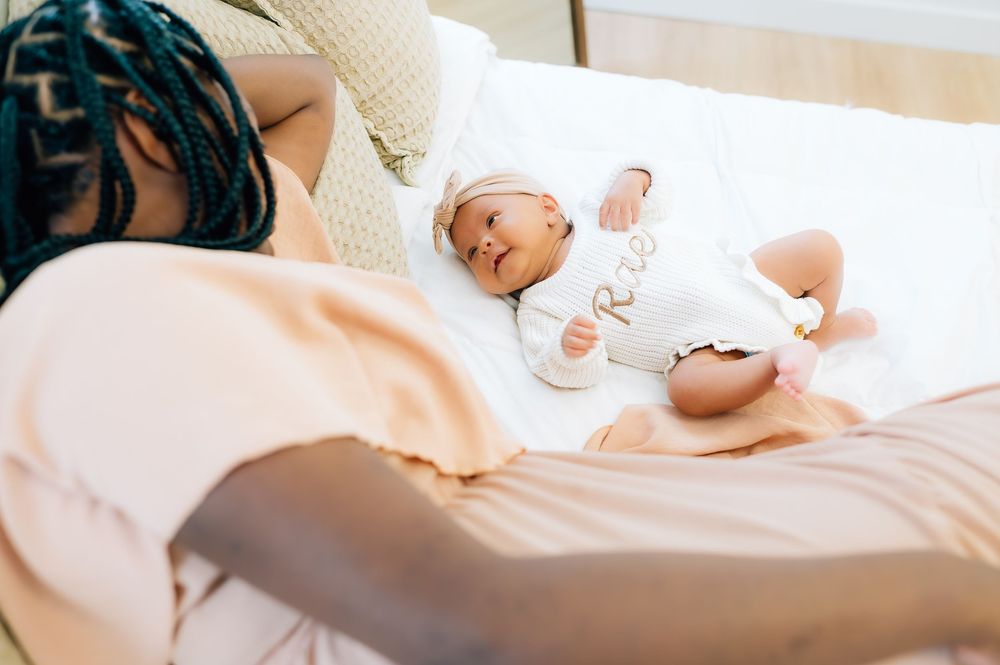 A small infant wearing white lies peacefully on a soft blanket.