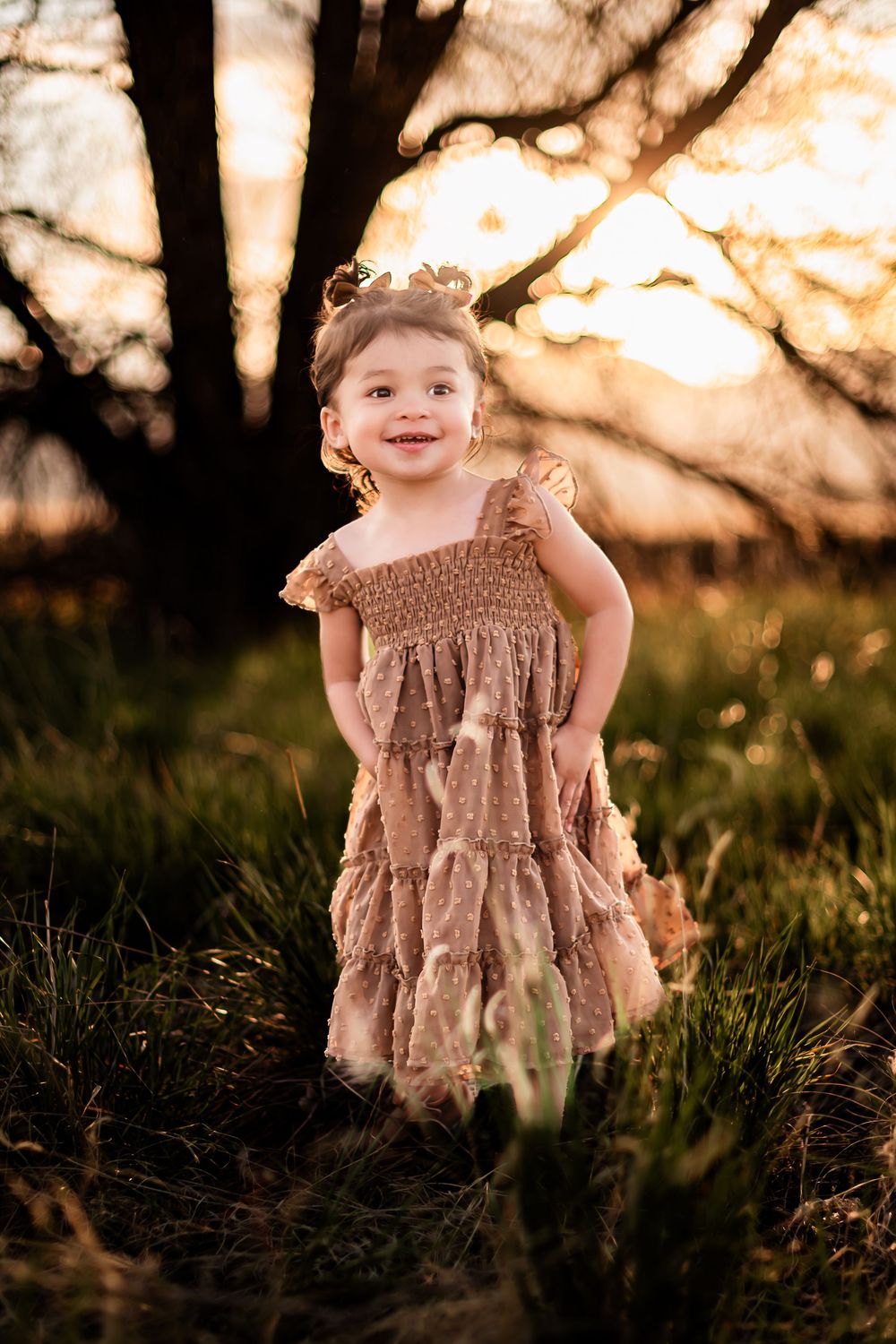 A ruffled tiered brown dress photographed in a dreamy golden sunset setting.