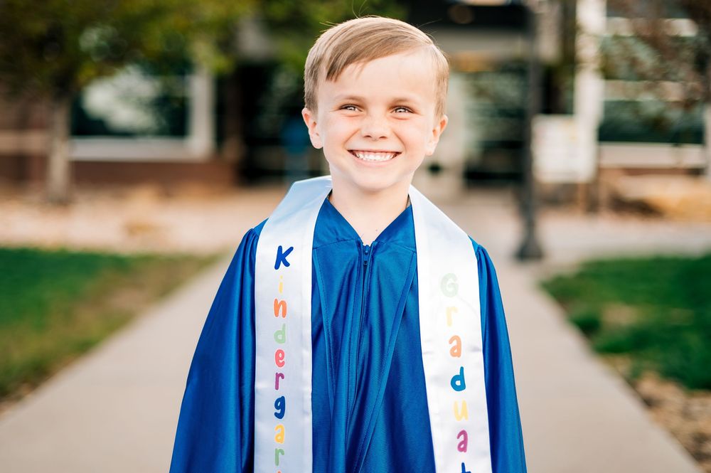 Graduate portrait session with student wearing blue graduation gown outdoors.