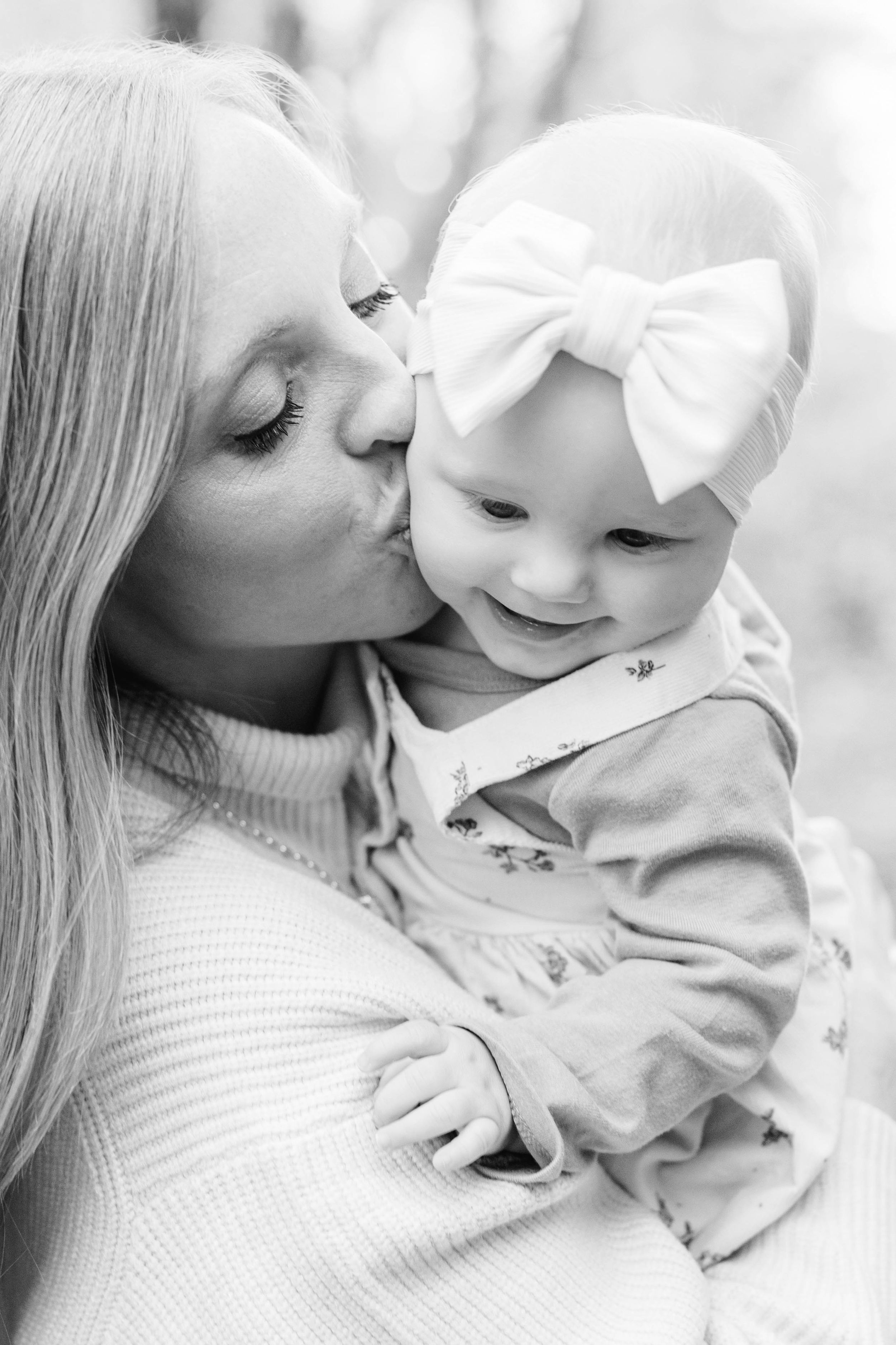 A tender black and white photo showing between a mom cuddling young baby girl during fall session in Clear Lake Iowa
