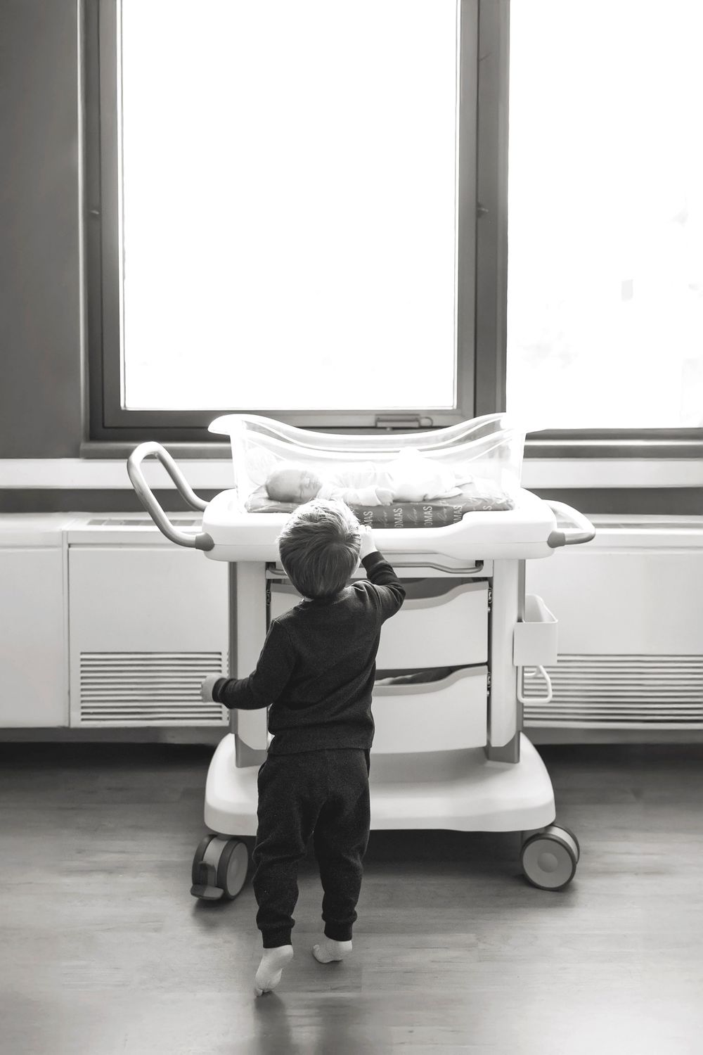 A sequence of black and white photos showing a person pushing a hospital bed along a corridor.