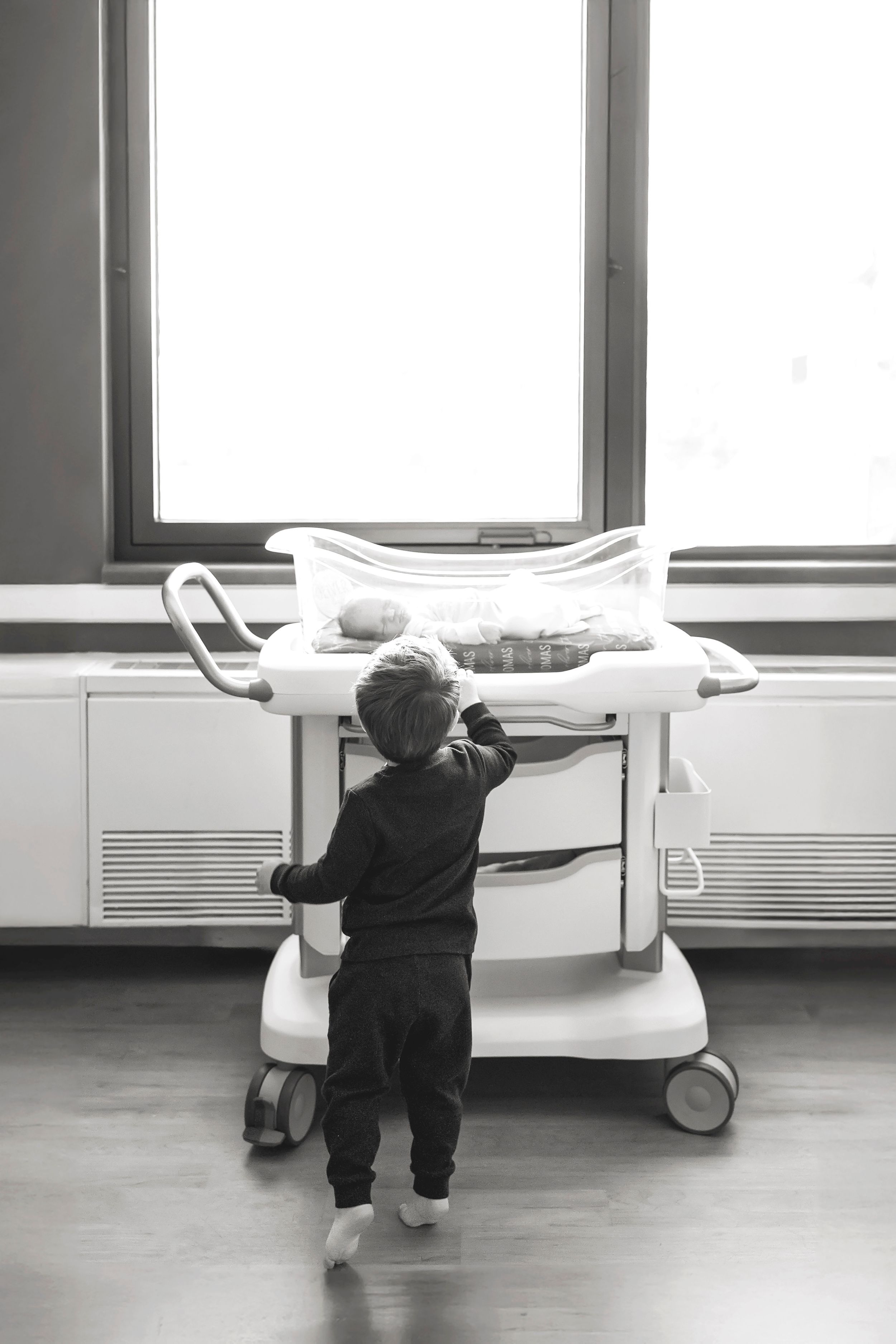 A sequence of black and white photos showing a person pushing a hospital bed along a corridor.