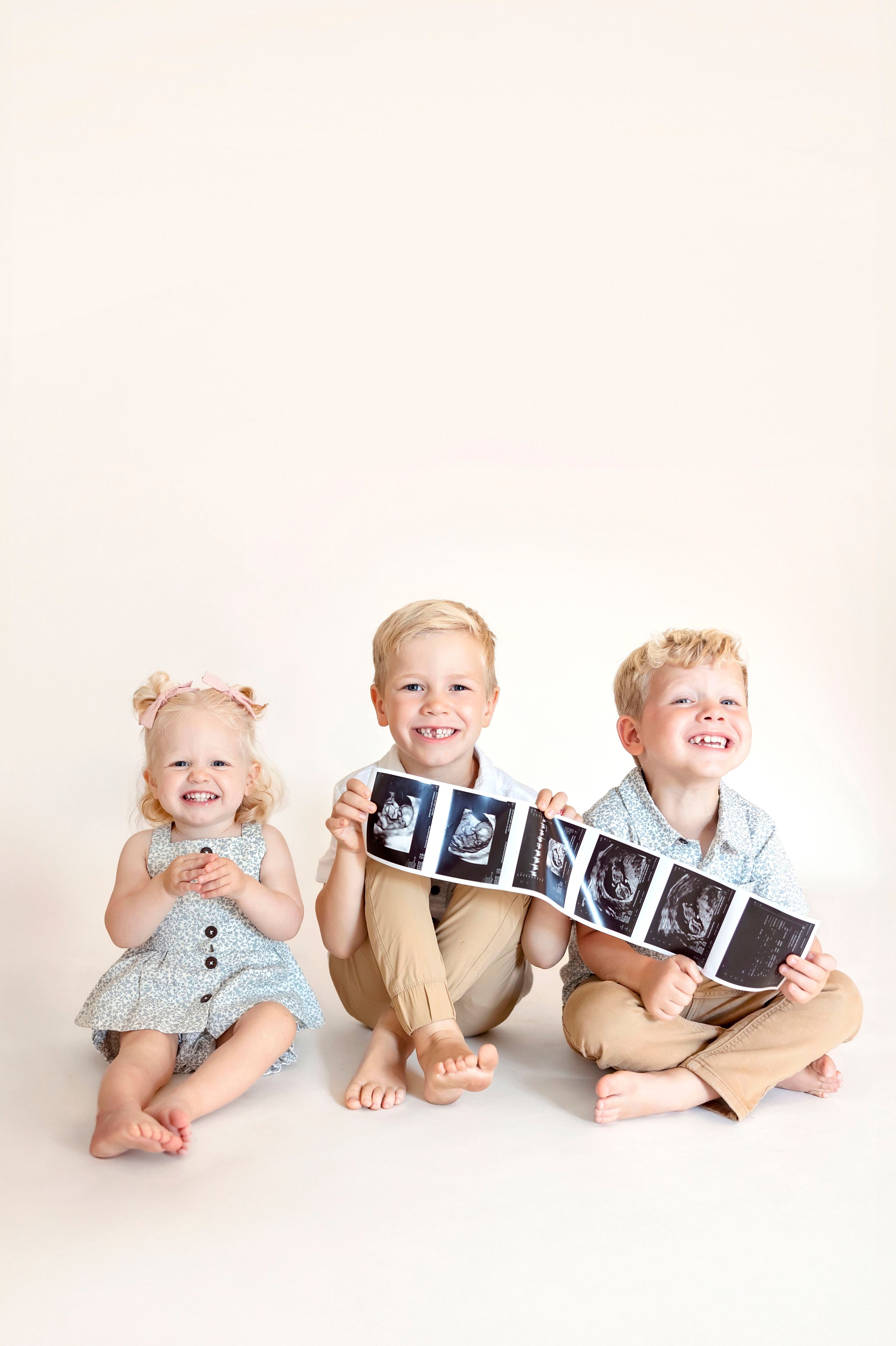 Three siblings holding ultrasound photos for a pregnancy announcement in Clear Lake, Iowa