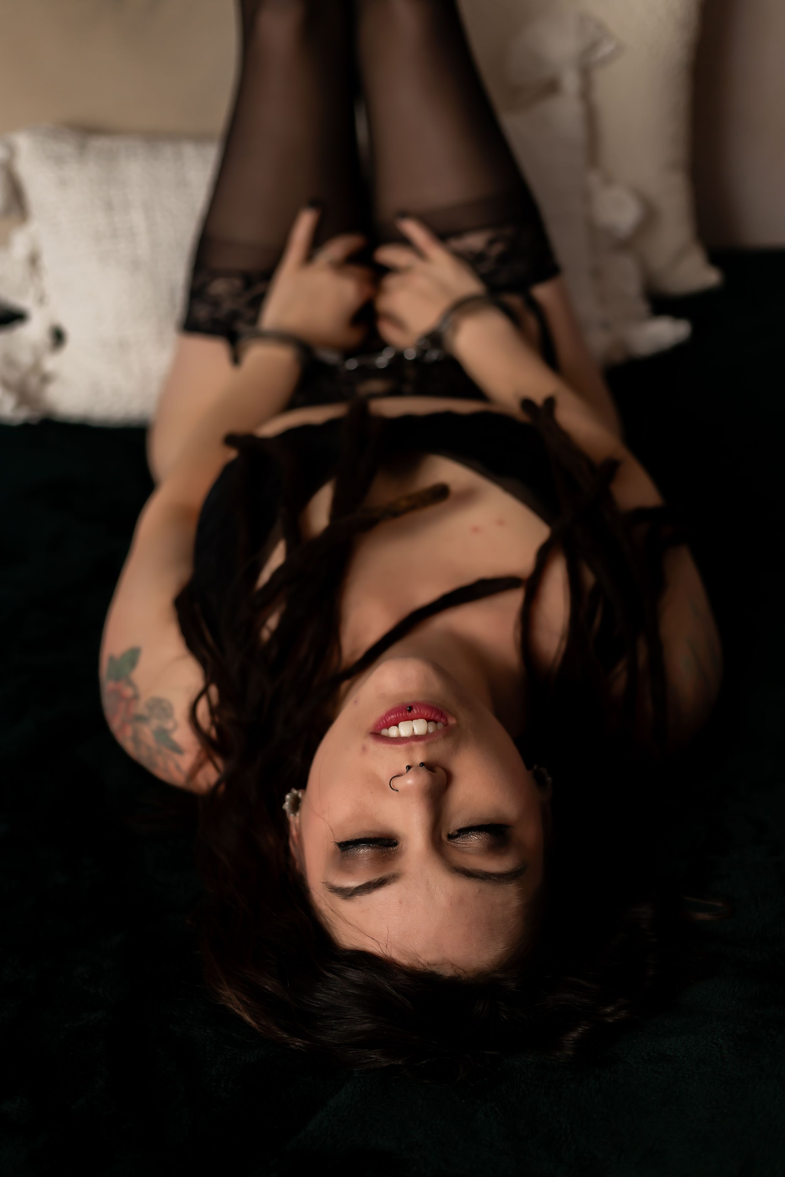 Intimate portrait in black lace lingerie on dark fabric with dramatic lighting.