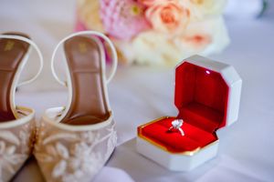 A collection of engagement rings in different boxes and settings displayed against pink and white floral backgrounds.