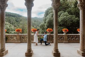Panoramic view of a stone colonnade terrace overlooking scenic mountains and forests on a cloudy day.