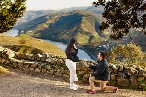 A romantic proposal scene overlooking a scenic mountain valley with a winding river and autumn foliage.