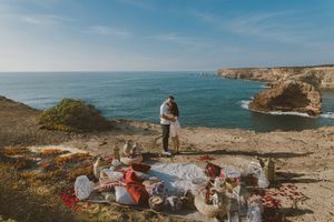 Group of people camping and enjoying scenic views along rugged coastal cliffs overlooking turquoise ocean waters.