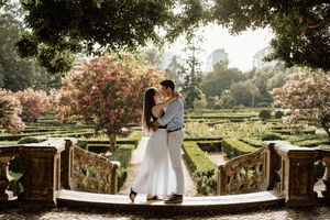 A romantic wedding ceremony setup with white chairs and floral decorations in a beautiful outdoor garden setting.