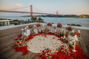 A romantic proposal setup with rose petals and candles overlooking the Golden Gate Bridge at sunset.