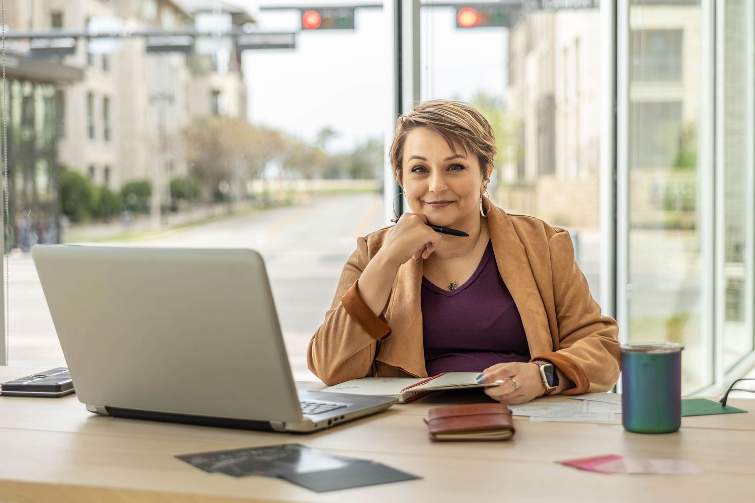 A woman poses in her office setting with a laptop.