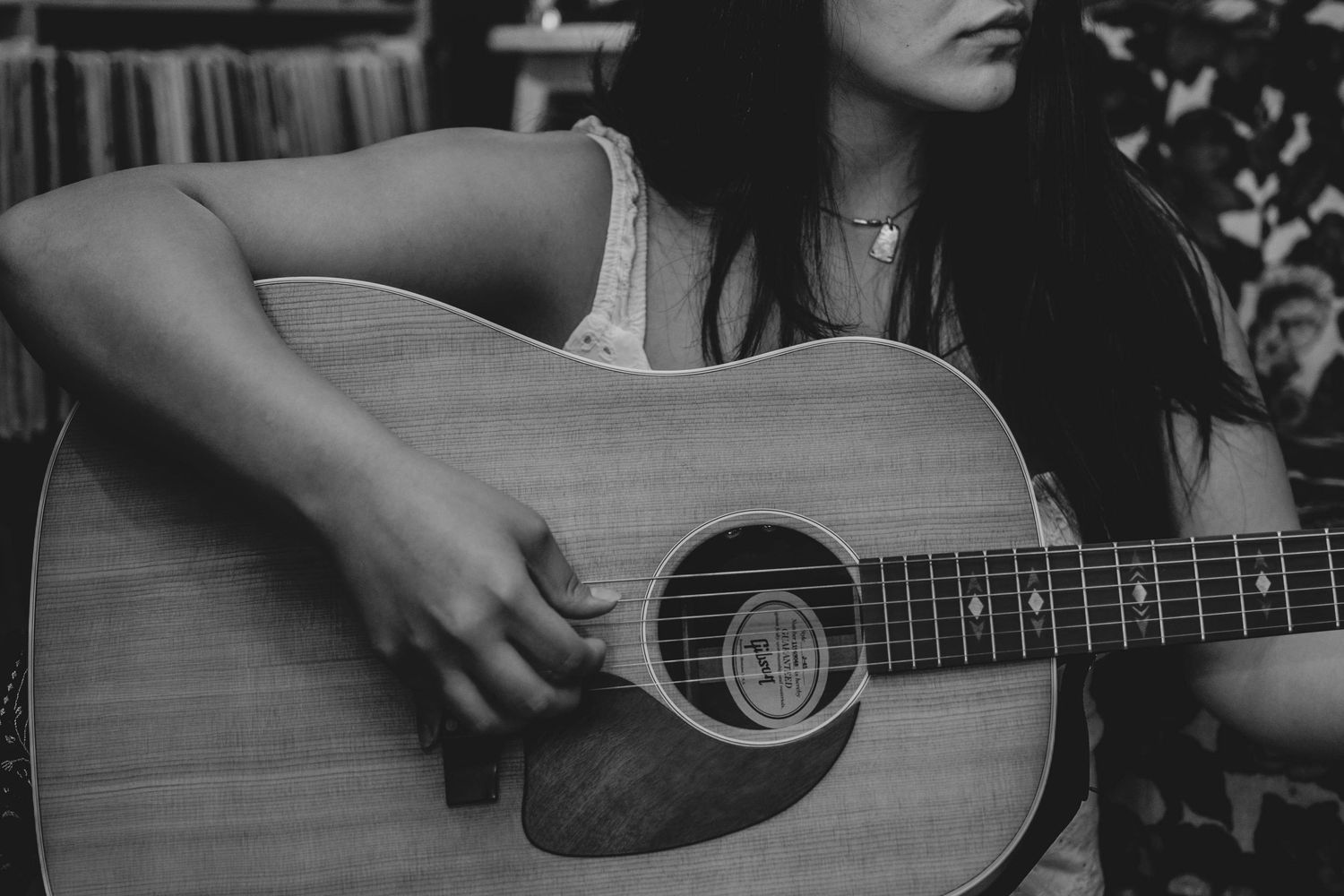 Black and white photo of a woman playing an acoustic guitar, strumming strings with focus and passion.