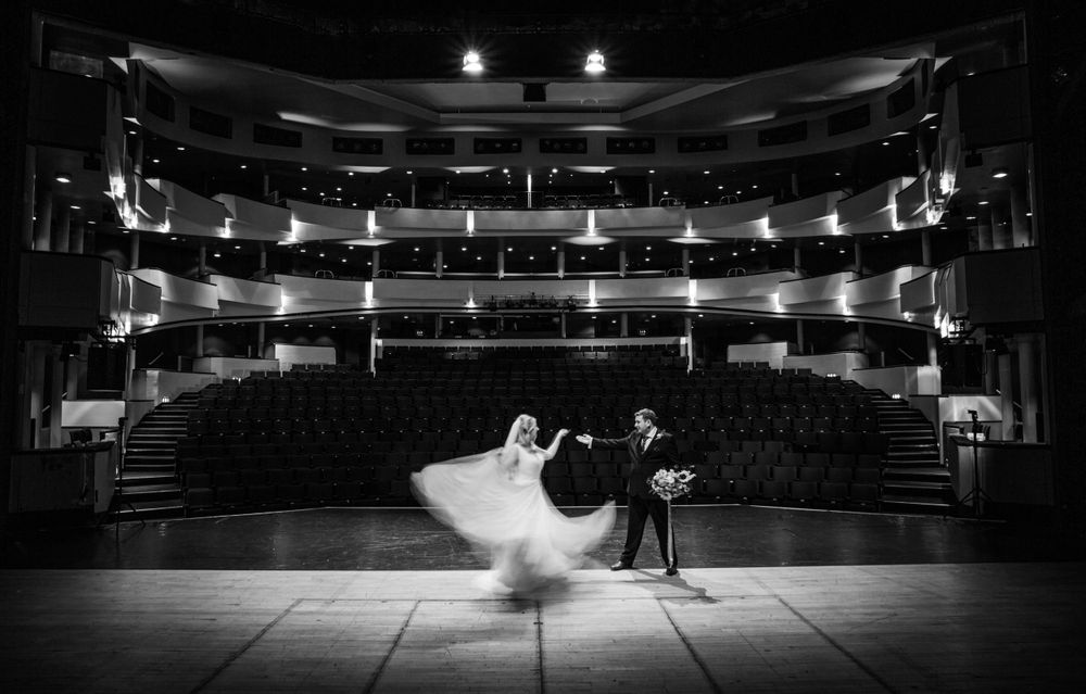 Dramatic black and white photo of dancers performing on an empty theater stage.