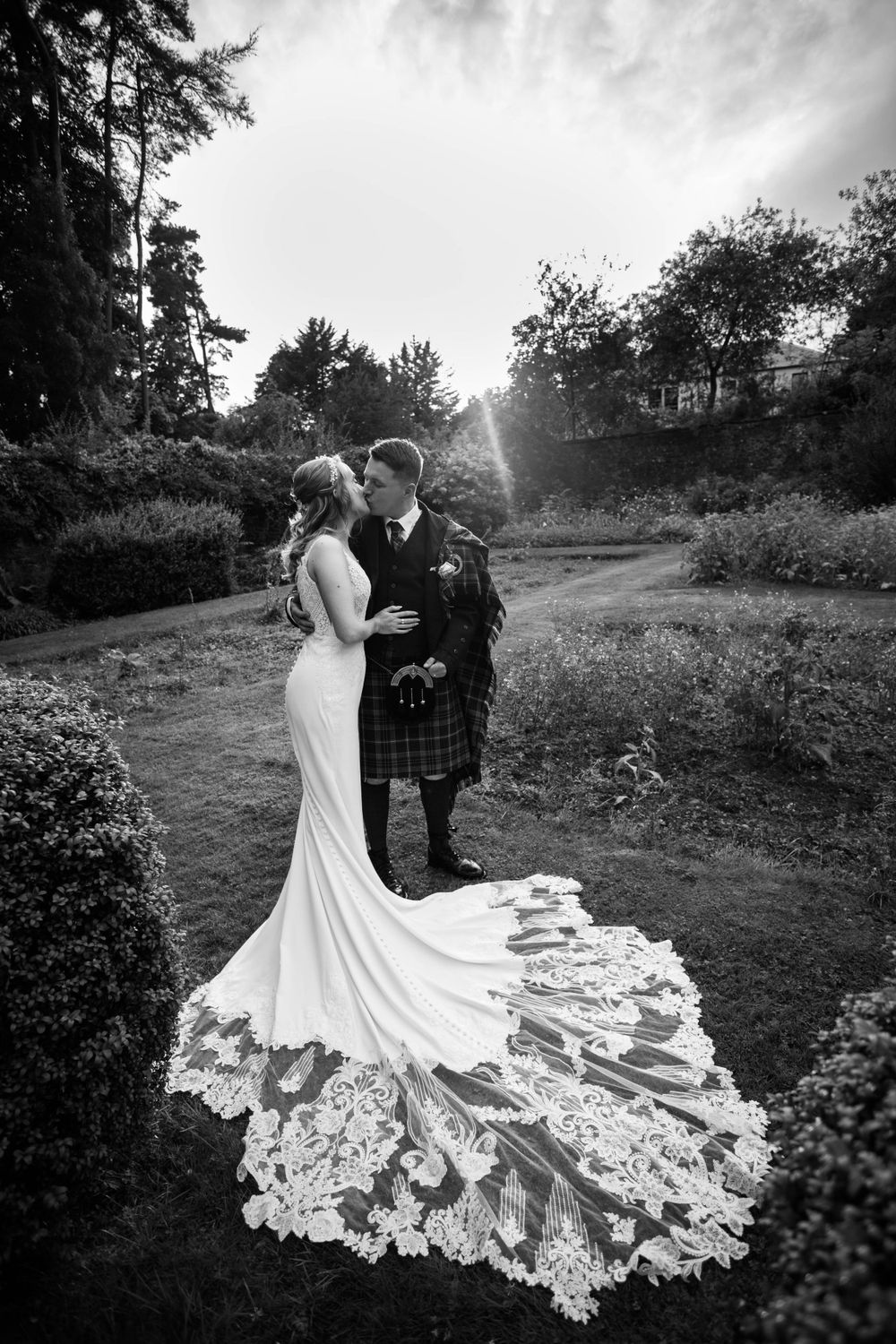 A romantic black and white portrait of newlyweds with a stunning lace wedding dress train.