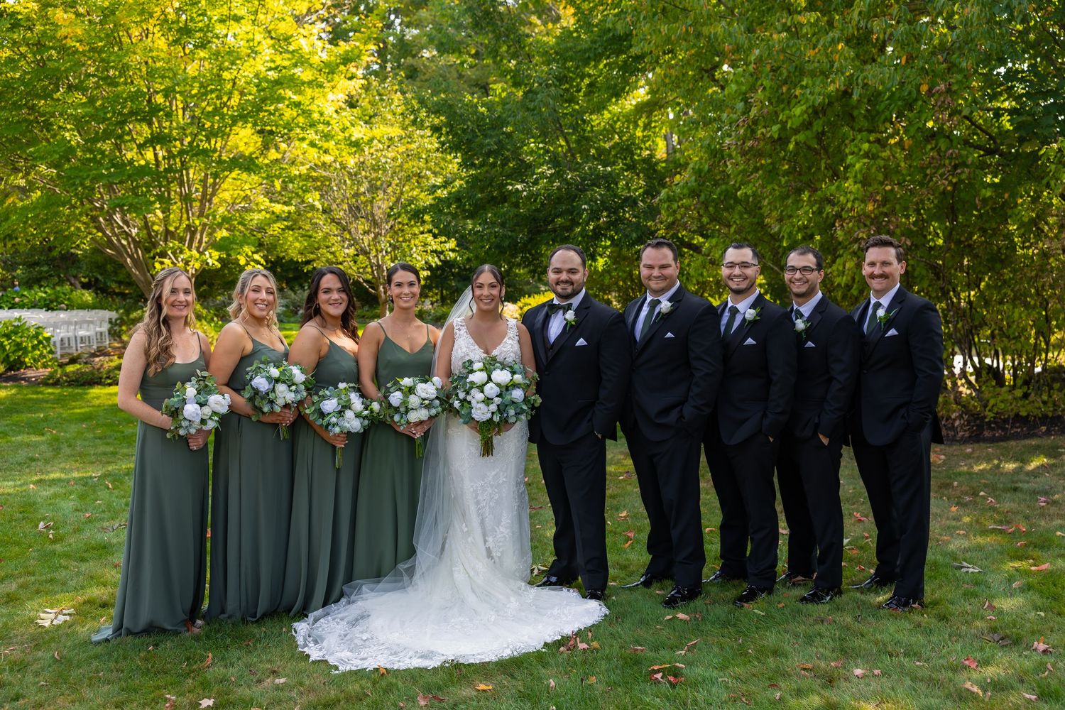 Wedding party wearing navy blue and gray poses in front of rustic red barn.
