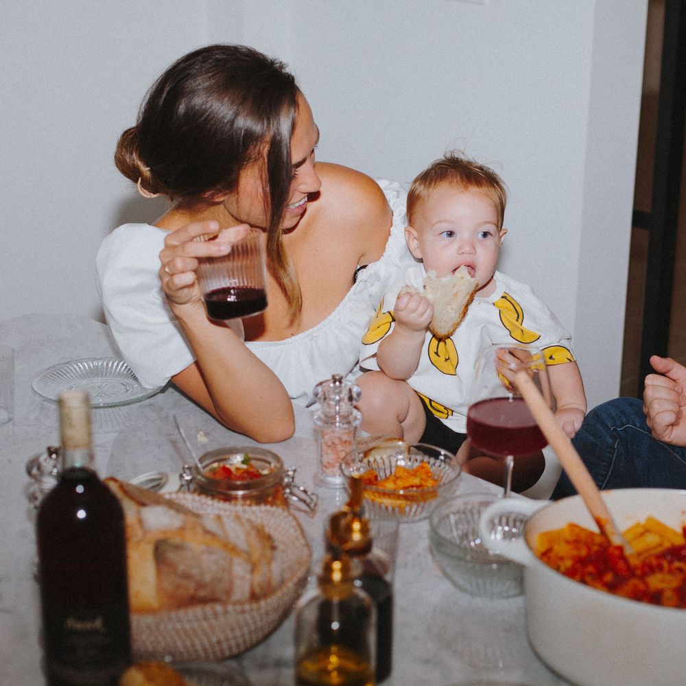People passing plates and sharing food across a dining table during a meal.
