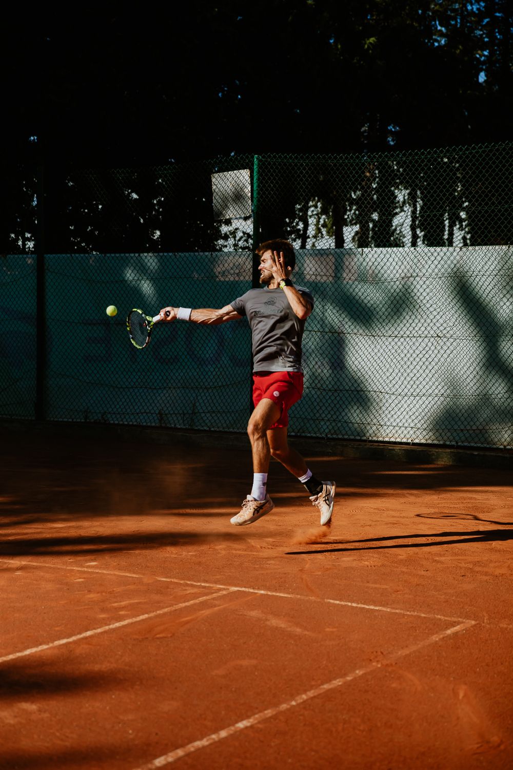 Tennis player hitting a forehand shot on a clay court during a sunny day - Cadart Country Tennis Académie - Aix-en-Provence - France