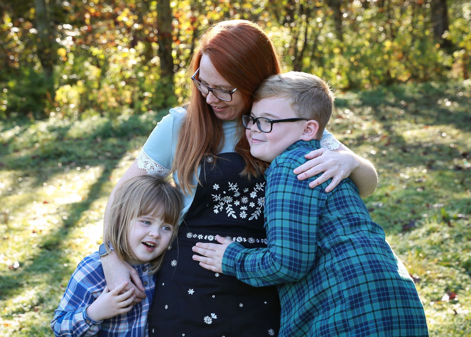 A moment of a mother with her two children, enjoying the outdoors and sharing a loving connection in a natural, relaxed photography session