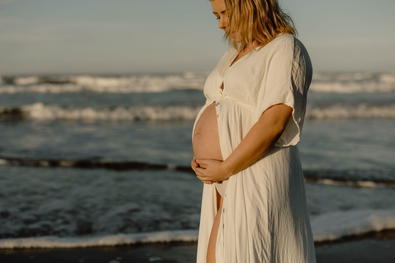 A romantic maternity photo shoot captured on a serene beach during sunset.