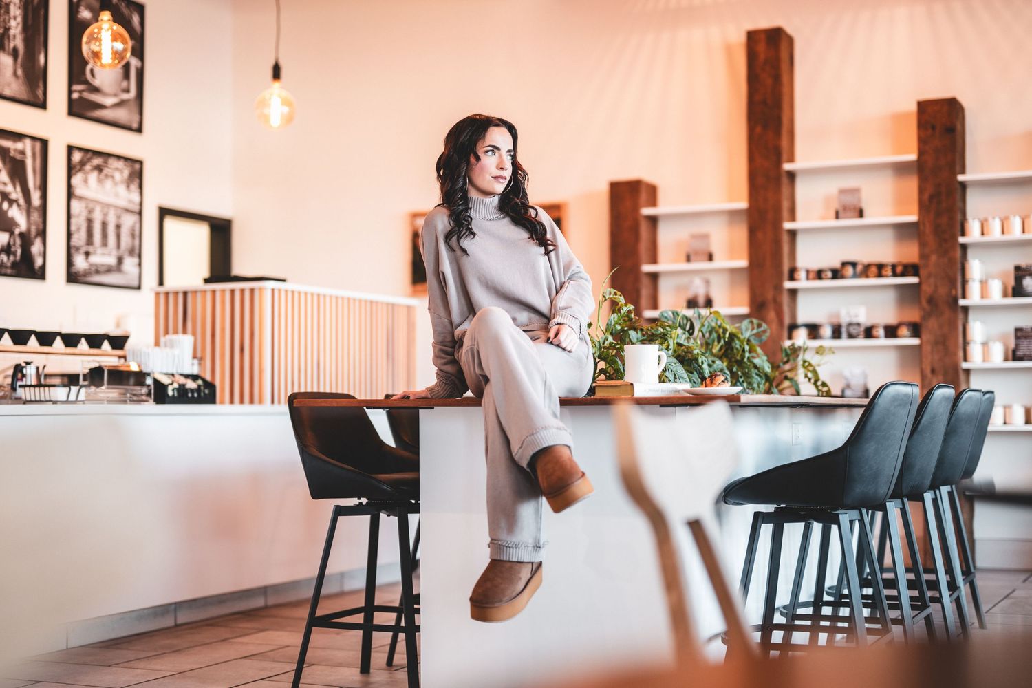 Modern coffee shop interior with wooden ceiling, framed wall art, counter service area and communal table seating.