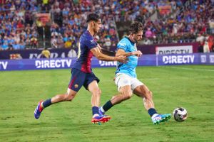 Soccer players competing for the ball during an intense match on a grass field.
