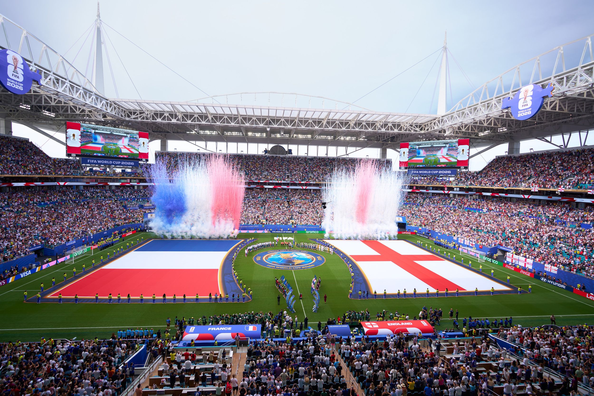 Colorful fireworks display over a packed stadium with French and English flags during a UEFA Euro opening ceremony.