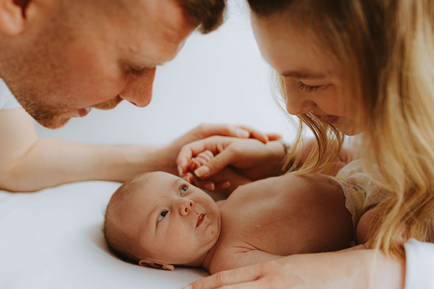 Tender family moment as parents share loving glances with their newborn baby.