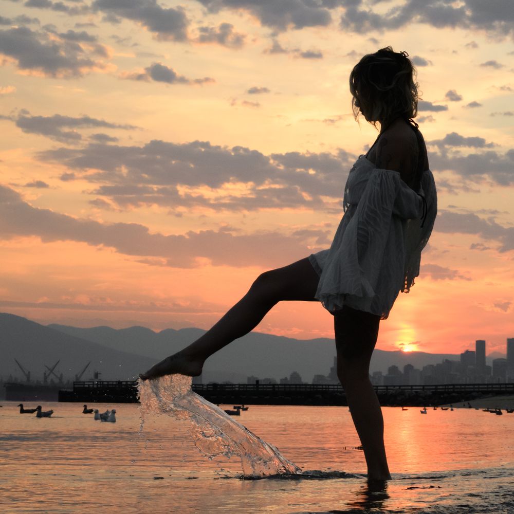 Woman silhouette kicking water at sunset, North Shore beach, North Vancouver photographer